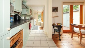 A kitchen with a dining area, wooden flooring, and a view through a glass door.