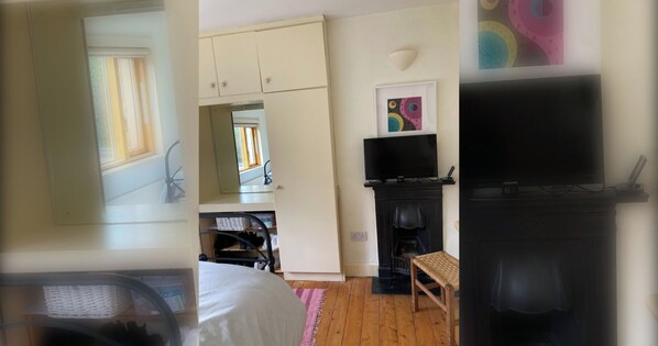 A room with a bed, a television, a fireplace, and a window.