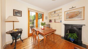 A dining area with a wooden table, chairs, a lamp, and a fireplace.