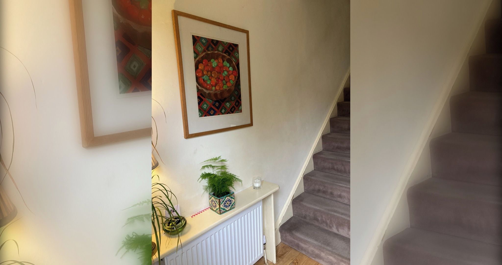 A staircase with a white railing and a wall with a framed picture and a potted plant.