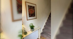 A staircase with a white railing and a wall with a framed picture and a potted plant.