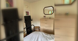 A bedroom with a bed, a dresser, a chair, and a TV.