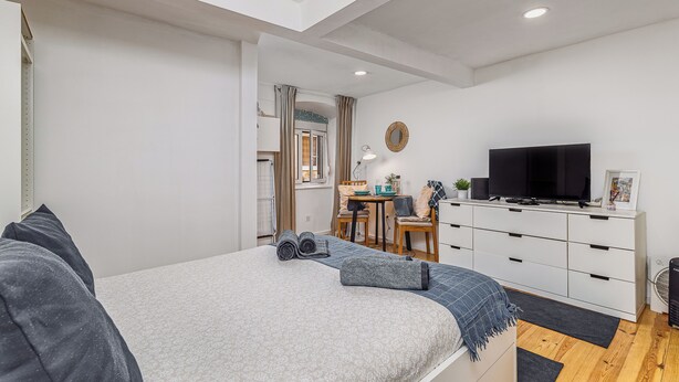 Una camera da letto moderna con un letto, una TV, una scrivania e una sedia.