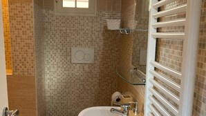 A bathroom with a white sink, toilet, and a glass shower enclosure. - Casa giardino San Pietro (Roma)