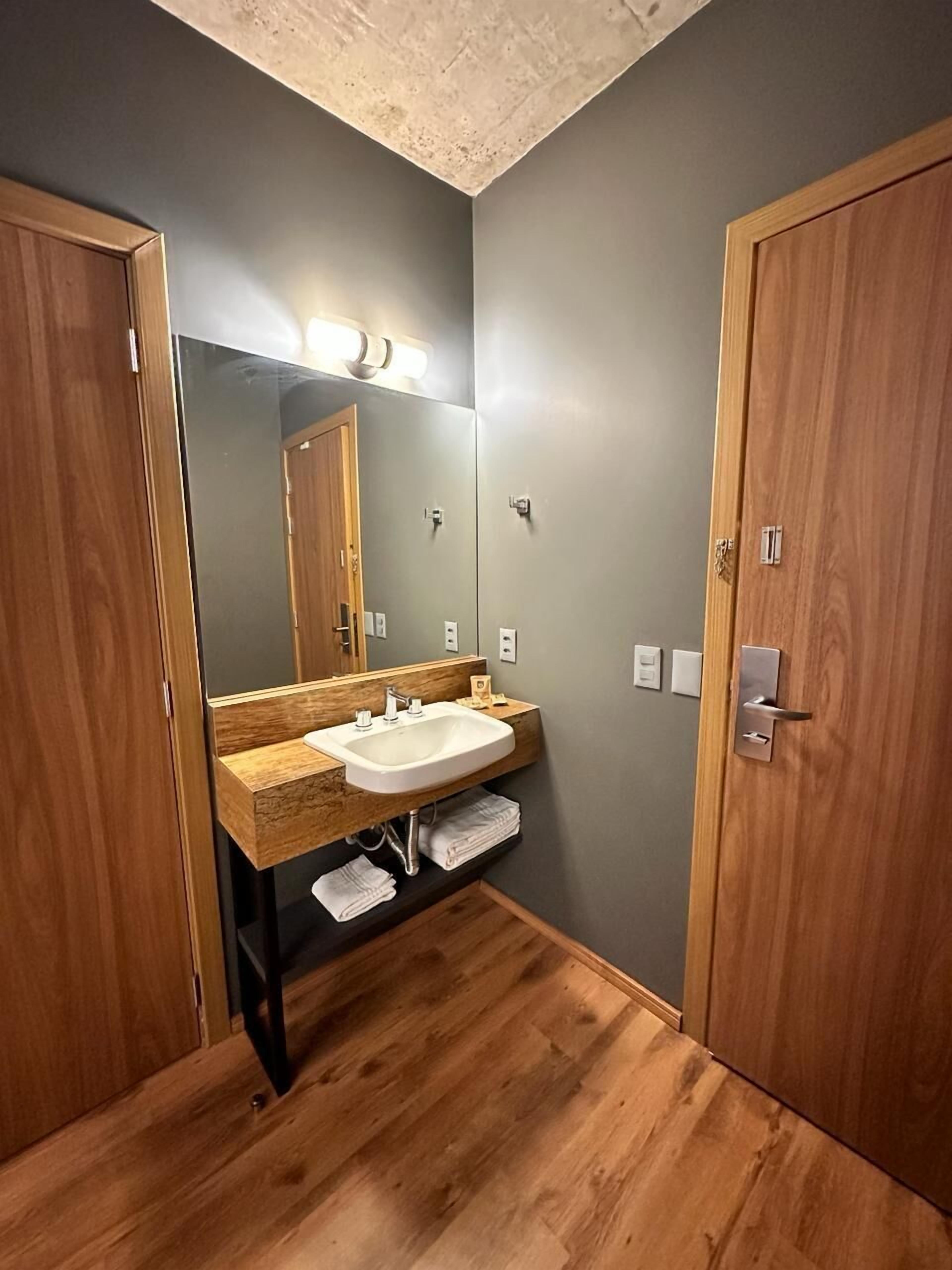 Un baño con tocador de madera, lavamanos y un espejo grande.