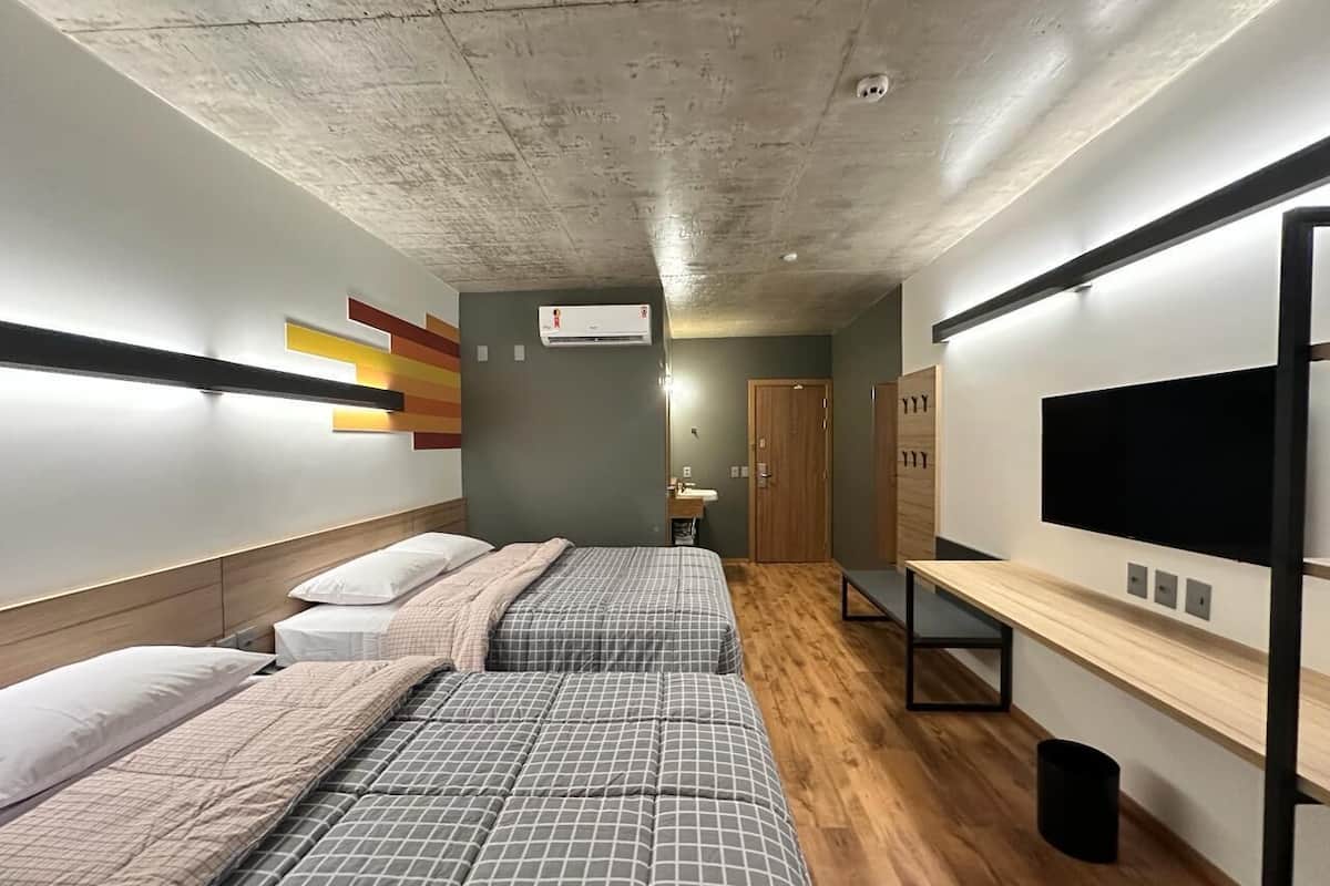 Habitación tipo dormitorio con dos camas, televisión, escritorio y armario.