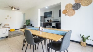 Un salon moderne comprenant un coin repas, une cuisine et un ventilateur de plafond.