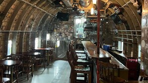 Un intérieur doté d’un plafond incurvé, de tables, de chaises, d’un espace bar et de divers équipements.