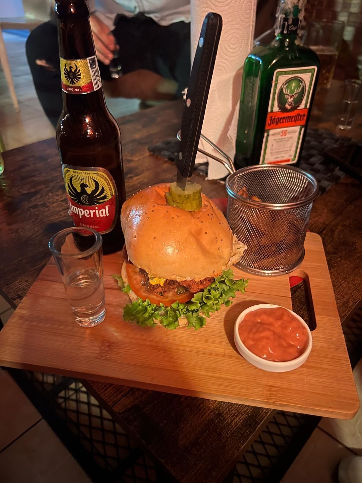 Un pasto con un hamburger, una bevanda e salse su un tavolo di legno.
