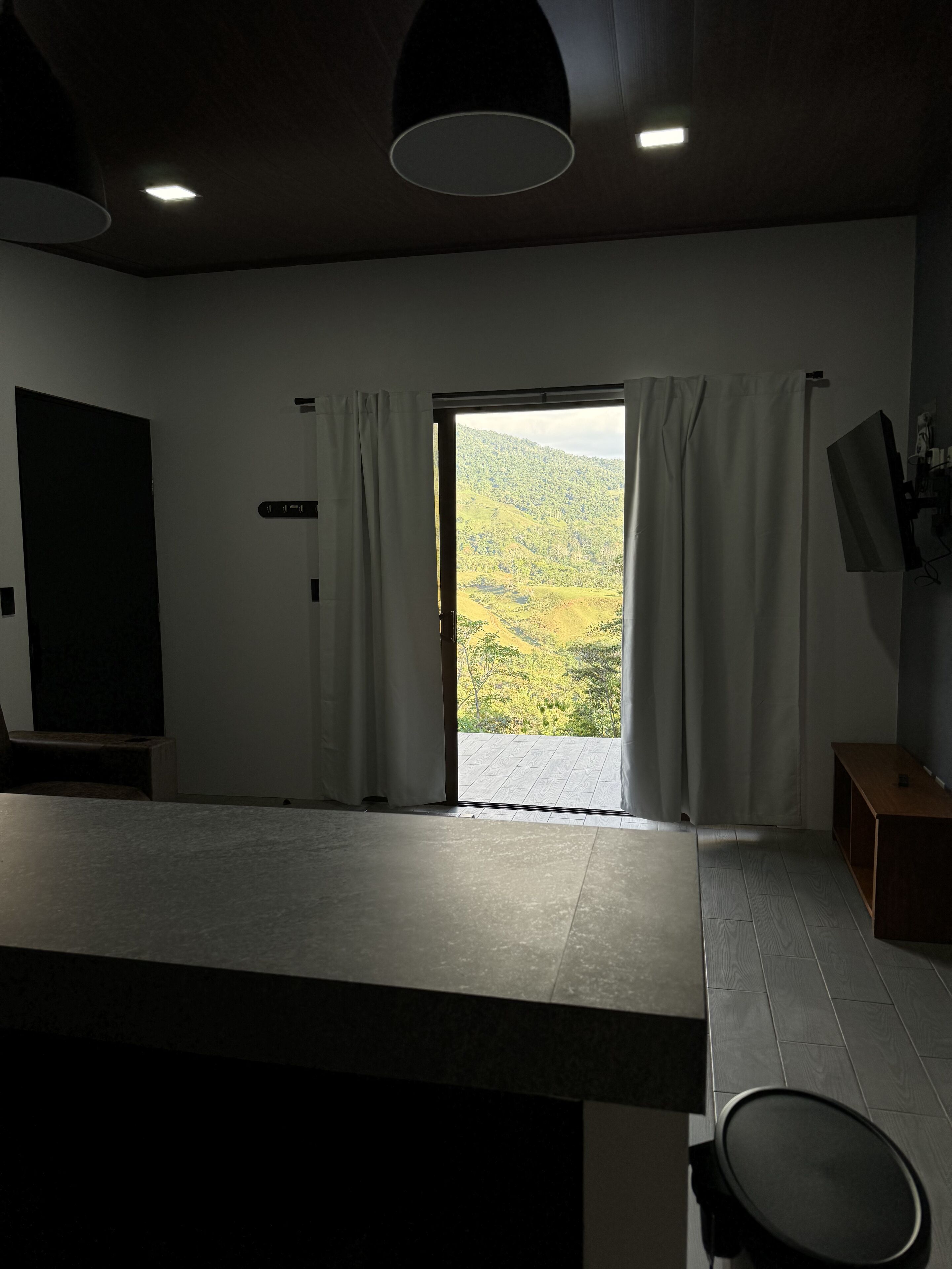 Een moderne kamer met een groot raam, een flatscreen televisie en een houten bank.