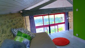 A room with a bed, a window with red frames, a green wall, and a red rug. - Joli Gîte Rural Pour un Séjour à la Campagne (DIEULIVOL)