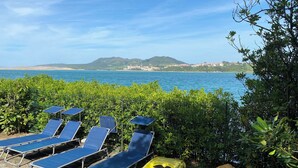 A beachside area with lounge chairs and kayaks, overlooking a coastal view with hills in the distance. - Cabaña de Ensueño en el Bosque y Junto al Mar. Ideal Pareja ,dos Niños y Mascota (Miengo)