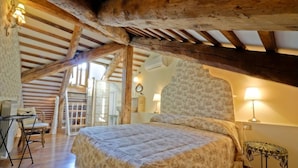Un dormitorio con una cama grande, vigas de madera, un escritorio y una silla.
