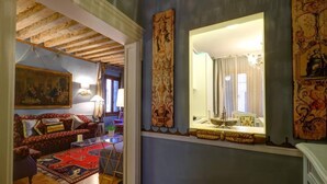 Un salón acogedor con un sofá rojo estampado, una mesa de centro de vidrio y suelo de madera.