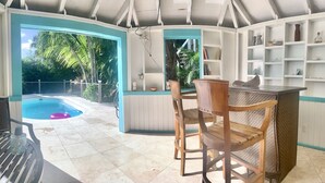 Ein Poolbereich mit Whirlpool, Holzstühlen und einer Bar mit Regalen.