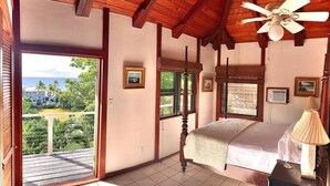 A bedroom with a bed, a ceiling fan, a nightstand, and a view of the outdoors.