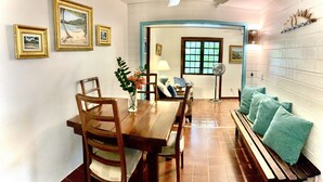A dining area with a wooden table, chairs, and a bench with teal cushions. There are framed pictures on the wall and a ceiling fan above. - Azul La Mer - Aqua Bay Villas (Cruz Bay)