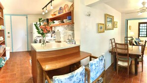 A kitchen with a wooden bench, a dining table with chairs, and a refrigerator. - Azul La Mer - Aqua Bay Villas (Cruz Bay)
