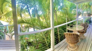 A balcony with a wicker table and chairs, surrounded by lush green foliage. - Azul La Mer - Aqua Bay Villas (Cruz Bay)