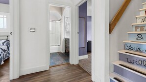 Un pasillo con una escalera de madera y una puerta que da a un baño.