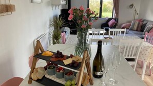 Un coin repas avec une table en marbre mise pour un repas, comprenant une planche de fromages, des raisins, des olives et du pain. On peut également apercevoir une bouteille de vin et des verres.