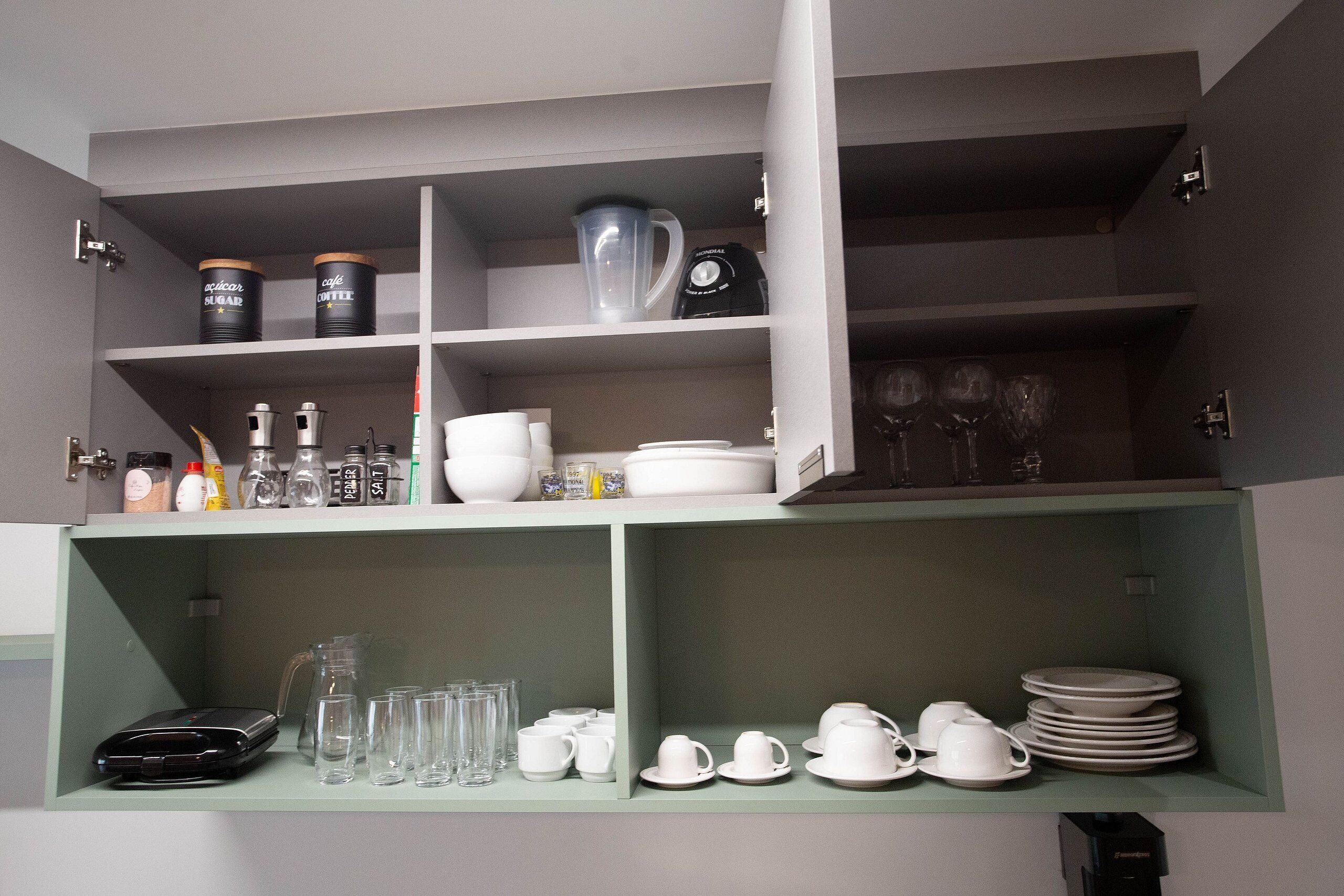 A kitchen with open cabinets displaying various kitchenware and appliances.
