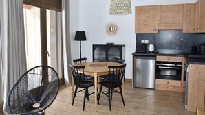 A modern kitchen with wooden cabinets, a dining area with a round table and chairs, and a hanging light fixture.