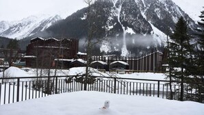 A snow-covered mountain with a wooden fence and buildings in the foreground.