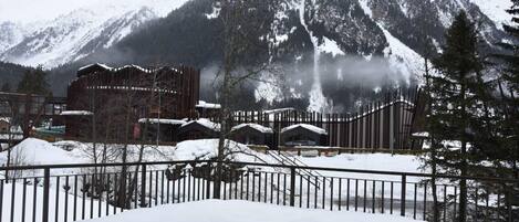 A snow-covered mountain with a wooden fence and buildings in the foreground.