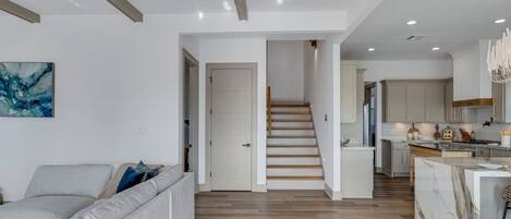 A modern interior with a staircase leading to a kitchen area, a living room with a sofa, and a dining area with a marble island.