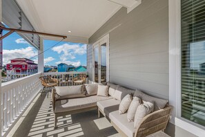 Un balcon avec un canapé, des fauteuils en osier et une table.