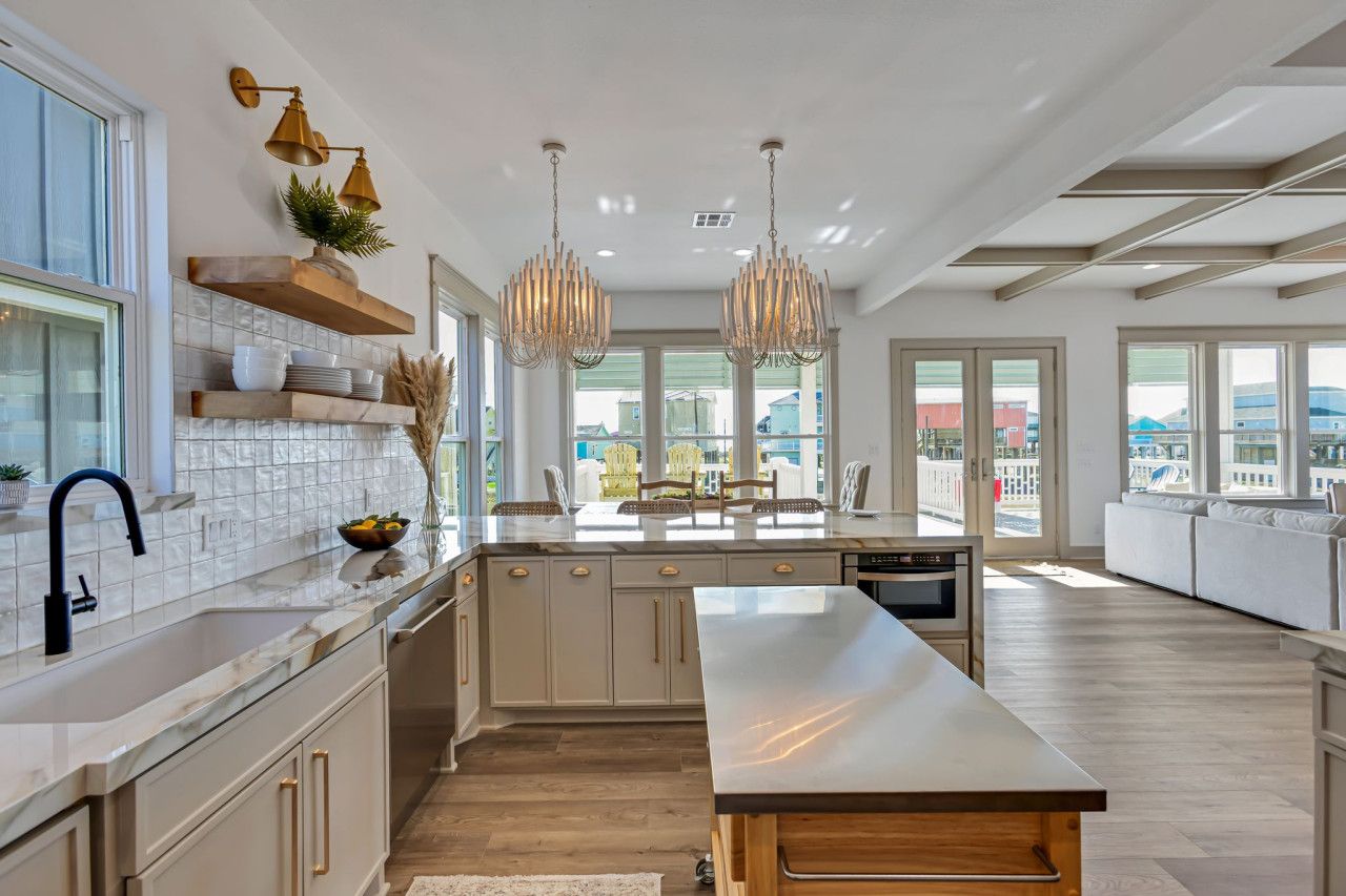 A modern kitchen with a large island, pendant lighting, and a view to the outside.