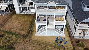 Une maison à deux étages avec un balcon au deuxième étage, une cour clôturée et un espace extérieur aménagé pour s’asseoir.