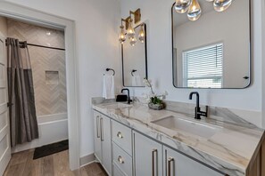 Une salle de bain moderne avec un double vasque, un grand miroir et un espace douche.