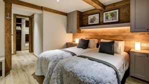 A bedroom with a large bed, wooden beams, a wardrobe, and framed pictures on the wall. - Chalet, 200m from ski slopes, Ground floor, balcony, tv, ski locker, 150m², La Plagne (Aime)