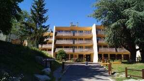 Et hotel med flere etager, en gul facade, balkoner og et skilt med teksten "Le Moniikos".