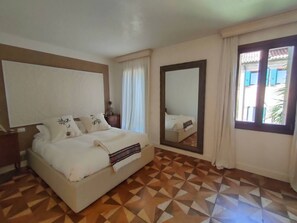 A bedroom with a bed, a large mirror, and patterned flooring. - LA Grande Bellezza (Venezia)