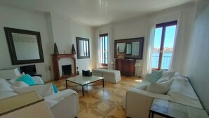 A spacious living room with two white sofas, a coffee table, and a fireplace. - LA Grande Bellezza (Venezia)