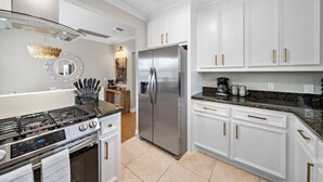 A modern kitchen with white cabinetry, stainless steel appliances, and a granite countertop. - The Queen’s Gambit II (Houston)