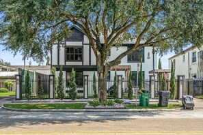 A two-story house with a large tree in front, a gated driveway, and a clear sky. - 1st Floor Near MD Anderson | Free Parking | Pets (Houston)