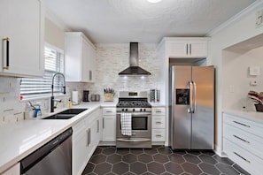 A modern kitchen with white cabinetry, a stainless steel refrigerator, a gas stove, and a dishwasher. - 1st Floor Near MD Anderson | Free Parking | Pets (Houston)