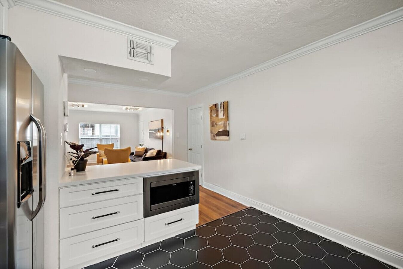 A modern kitchen with white cabinetry, a built-in oven, and a stainless steel refrigerator.