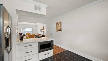 A modern kitchen with white cabinetry, a built-in oven, and a stainless steel refrigerator.