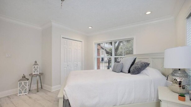 A bedroom with a bed, bedside table, lamp, and window with blinds.
