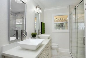 A modern bathroom with a glass shower enclosure, a white sink, and a toilet. - The Bishop's Haven 2 (Houston)