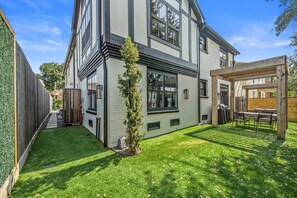 A two-story house with a covered patio and a well-maintained lawn. - The Bishop's Haven 2 (Houston)