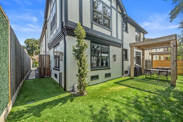 A two-story house with a covered patio and a well-maintained lawn.