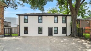 A two-story building with a flat roof, multiple windows, and a front door. - The King's Retreat I (Houston)
