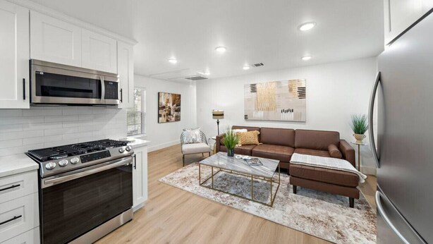 A modern kitchen with white cabinets, a stainless steel refrigerator, and a built-in oven. - The King's Retreat I (Houston)