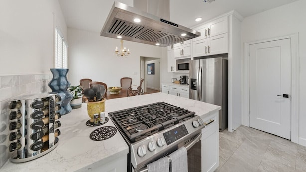 A modern kitchen with a central island, stainless steel appliances, and white cabinetry. - The King`s Castle II (Houston)